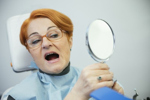 woman at dentist examines her teeth in mirror